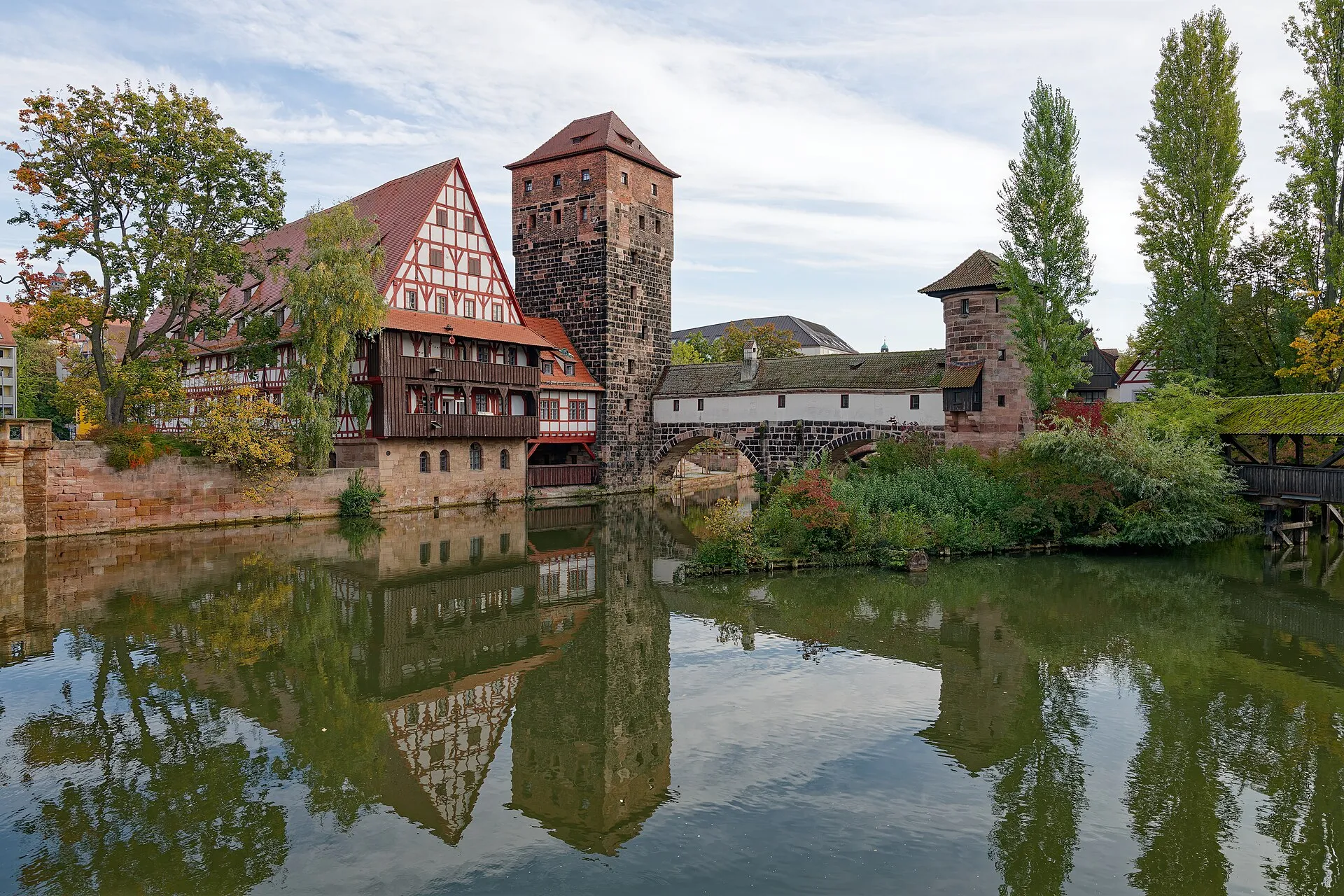 Fachwerkbau Weinstadel, Wasserturm und überdachter Henkersteg spiegeln sich in der Pegnitz in Nürnberg