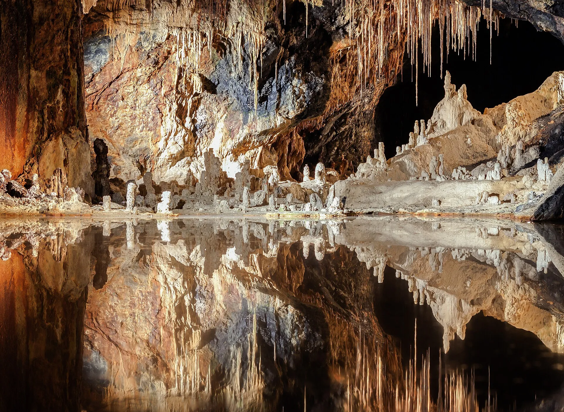 Weiße Tropfsteine spiegeln sich im stillen Wasser des Märchendoms in den Saalfelder Feengrotten